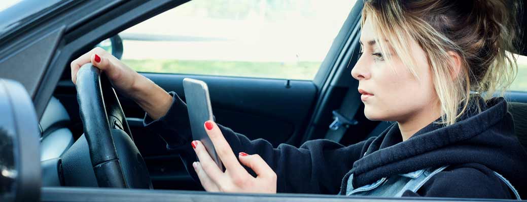 Woman driving while looking at her cell phone