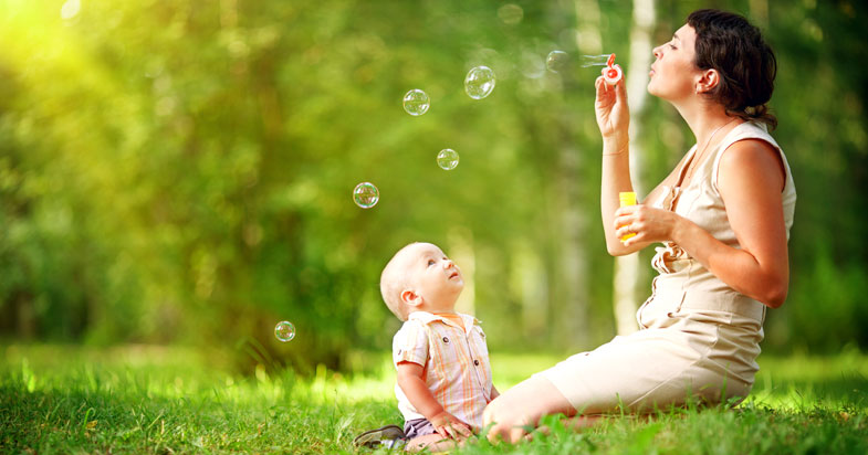 Mother blowing bubbles while toddler watches